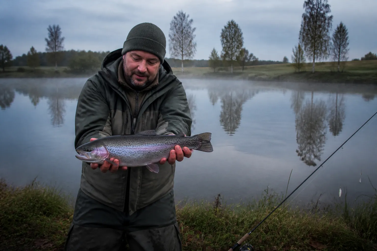 Angler hält eine frisch gefangene Regenbogenforelle an einem Forellensee in Schleswig-Holstein